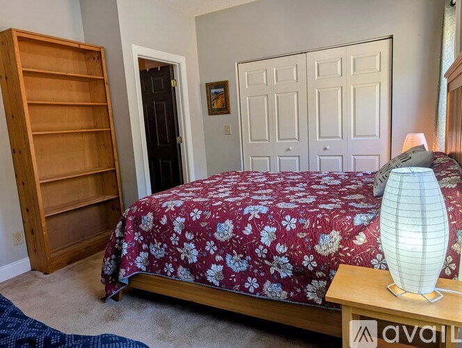 A bedroom with a bed, a lamp, and a bookshelf.