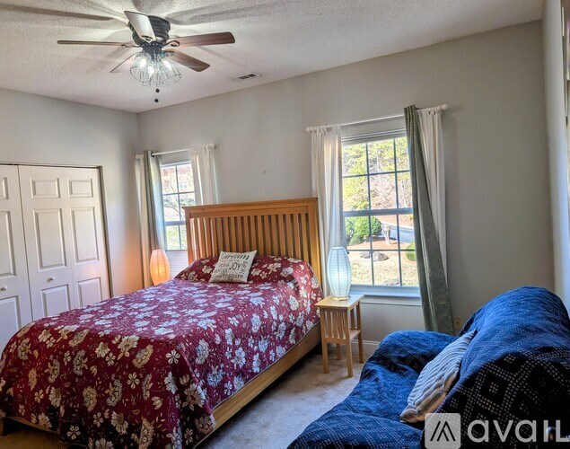 A bedroom with a red floral bedspread and a wooden headboard.