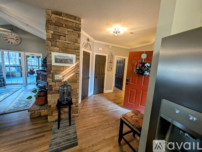 A living room with a stone fireplace and a flat screen TV.