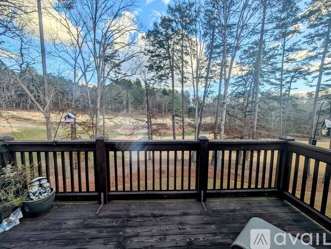 A wooden deck with a view of a field and trees.