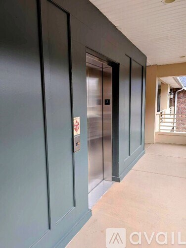 A hallway with a glass elevator doors and a no smoking sign.
