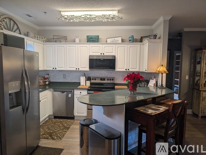 A kitchen with white cabinets and a stainless steel refrigerator.