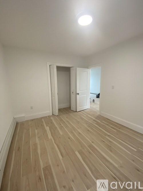 A room with wooden flooring and two doors.