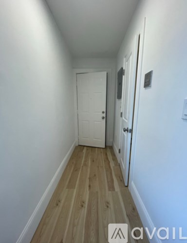 A hallway with a white door and wooden floors.