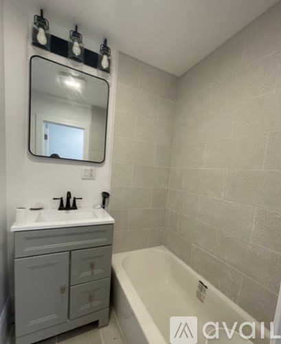 A bathroom with a white sink, a mirror, and a grey cabinet.