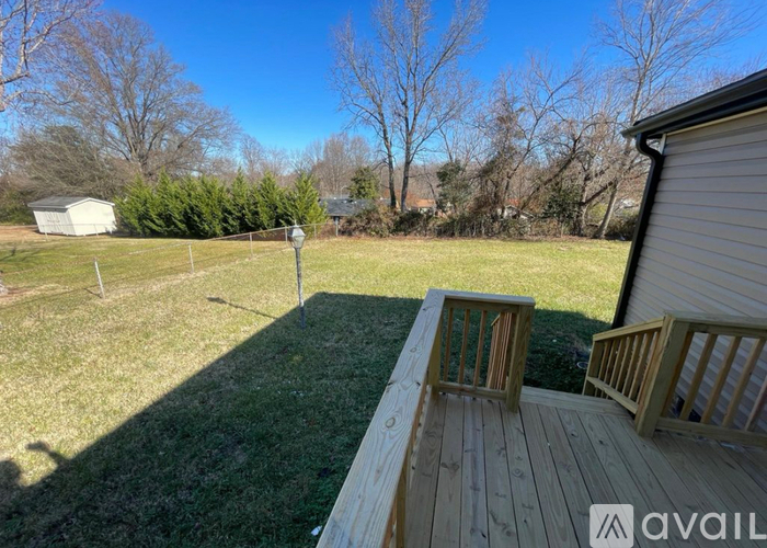 A wooden deck with a bench and a post in a backyard.