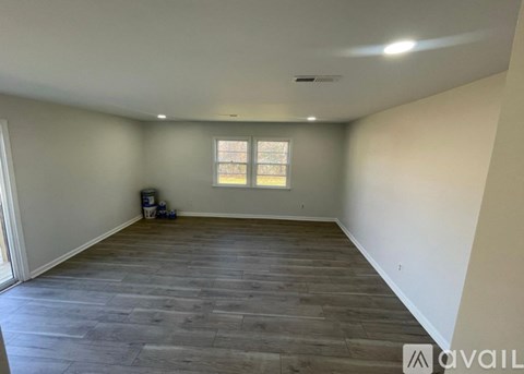 A spacious room with wooden flooring and a window.