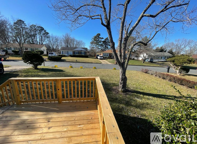 A wooden deck overlooks a grassy area with trees and houses in the distance.