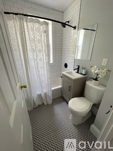 A white bathroom with a toilet, sink, and shower.