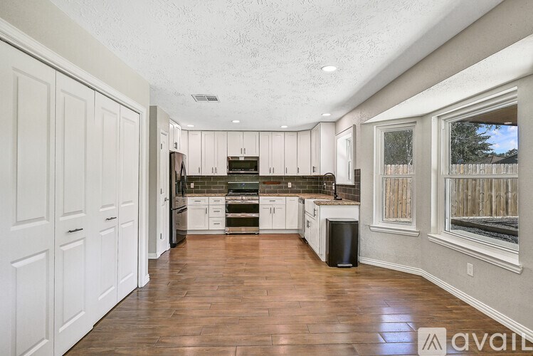 A kitchen with white cabinets and a wooden floor.