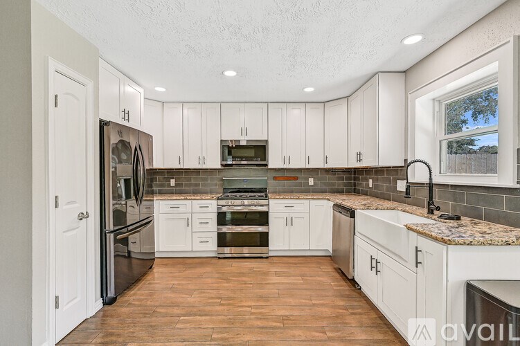 A kitchen with white cabinets and a tile backsplash.