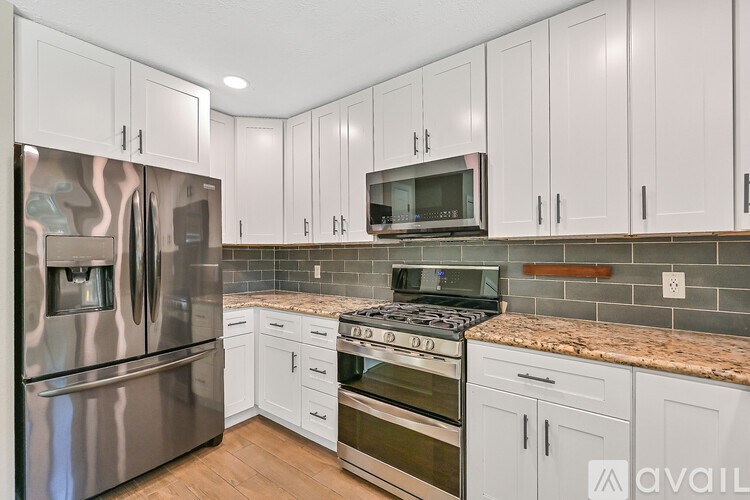 A kitchen with white cabinets and a granite countertop.