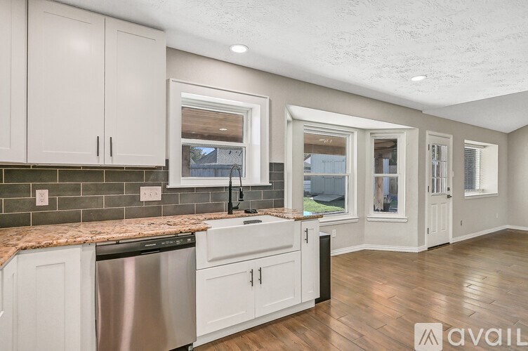 A kitchen with white cabinets and a granite countertop.