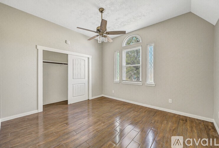 A room with a ceiling fan and a window with a view of trees.