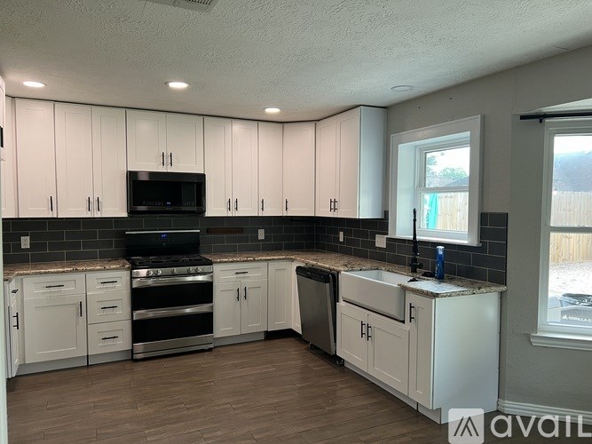 A kitchen with white cabinets and a black stove top oven.