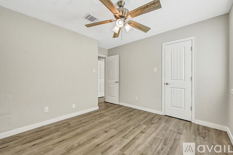 A room with a ceiling fan and wooden flooring.
