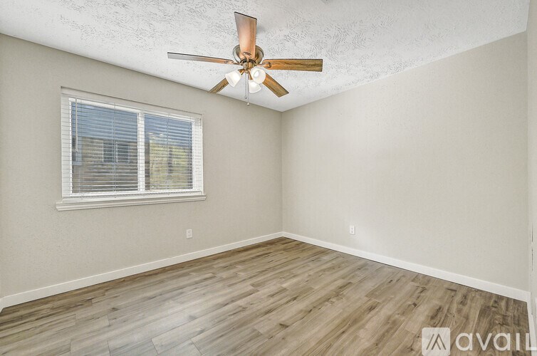 A room with a ceiling fan and a window with blinds.