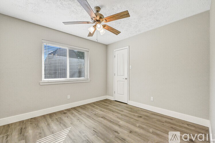 A room with a ceiling fan and a window with blinds.