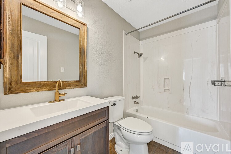 A bathroom with a white sink and a wooden framed mirror.