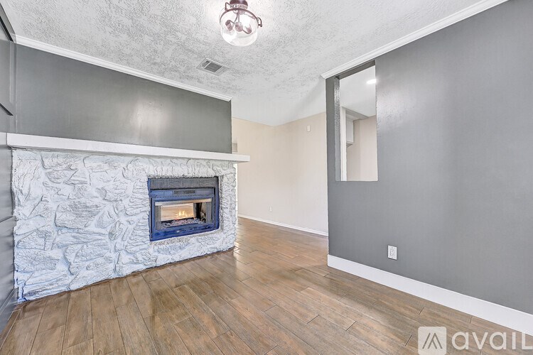 A room with a stone fireplace and wooden flooring.
