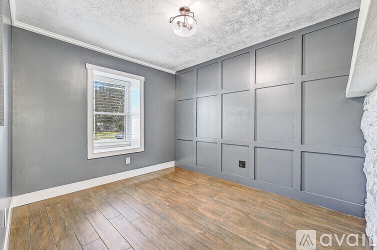 A room with wooden flooring and a window with blinds.