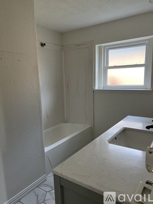 A bathroom with a tub, sink and window.