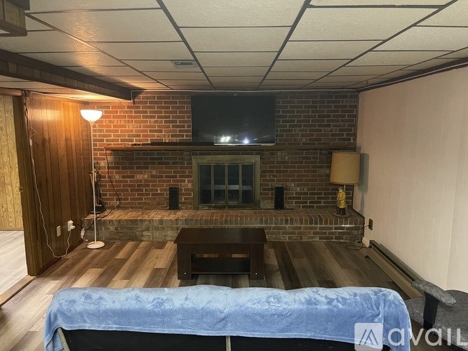 A living room with a brick fireplace and a flat screen TV mounted above it.