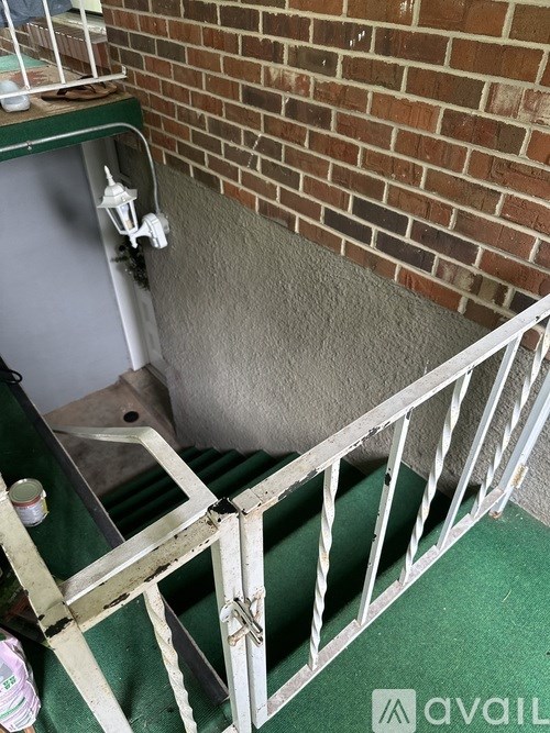 A white metal staircase with a green mat on the floor.