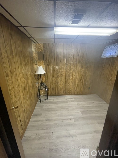 A room with wooden walls and a lamp on a table.