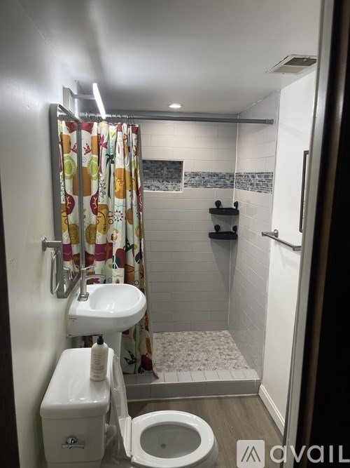 A small bathroom with a toilet, sink, and shower.