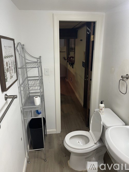 A white toilet with a toilet paper holder and a towel rack on the wall.