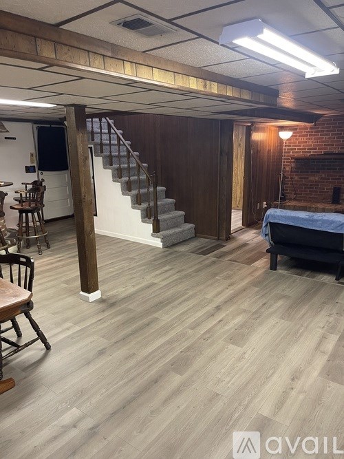 A room with wooden floors and a staircase leading to another room.