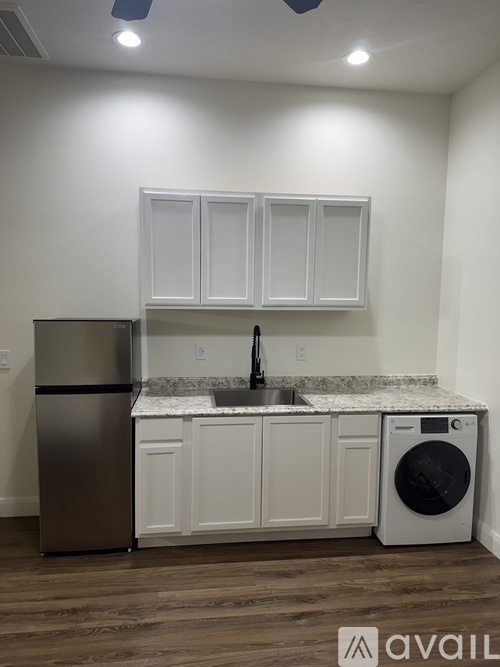 A kitchen with white cabinets and a marble backsplash.