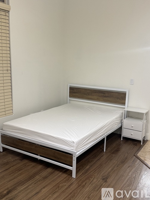 A white bed with a wooden headboard and footboard is in a room with wooden flooring.