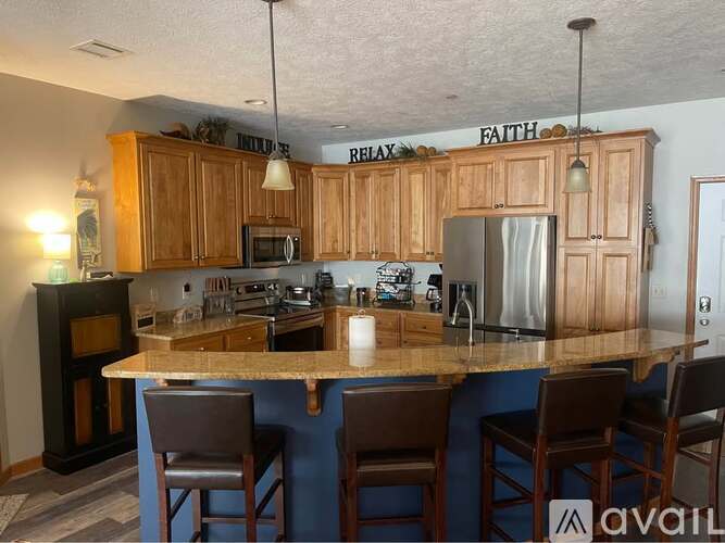 A kitchen with wooden cabinets and a bar area with stools.