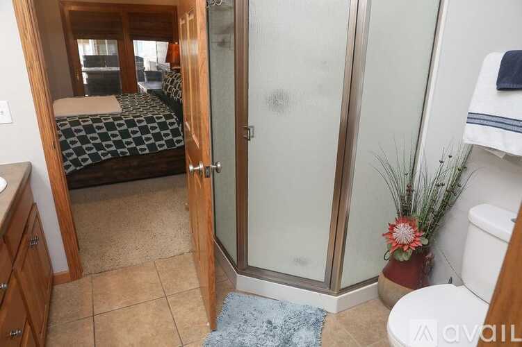 A bathroom with a toilet, sink, and a bedroom with a bed and a window.
