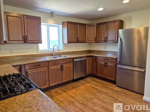 A kitchen with wooden cabinets and a stainless steel refrigerator.