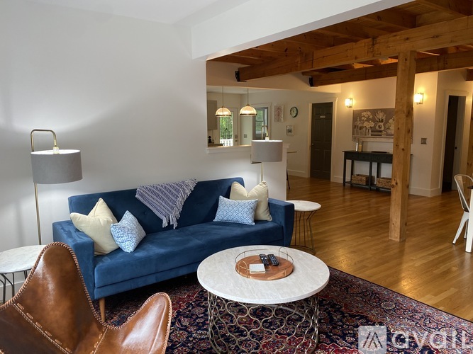 A living room with a blue couch and a brown leather chair.