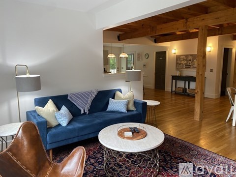A living room with a blue couch and a brown leather chair.
