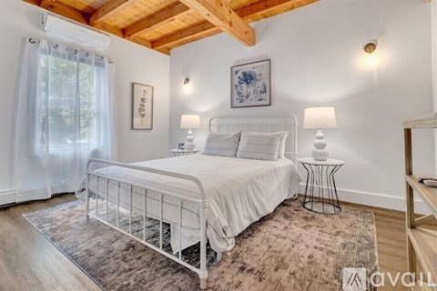 A bedroom with a white bed and a wooden ceiling.