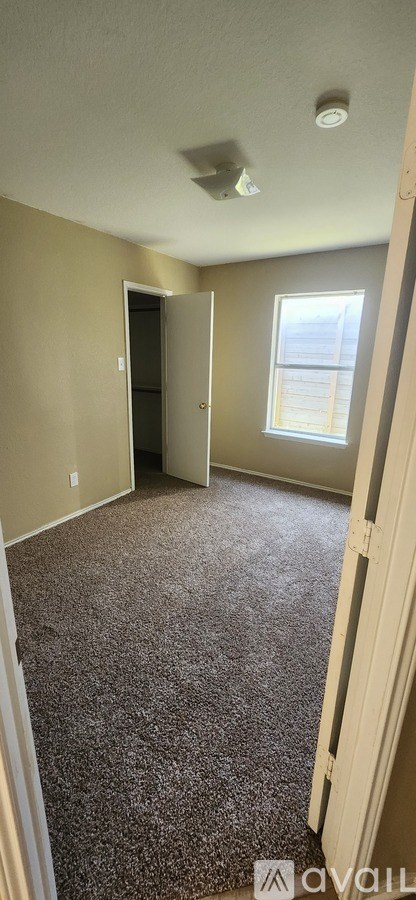 A room with carpet flooring and a doorway leading to another room.