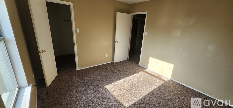 A room with carpeted floor and two doors.