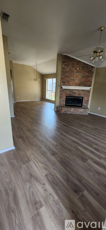 A room with wooden floors and a brick fireplace.