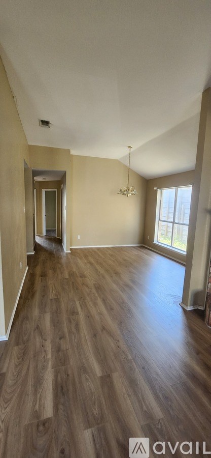 A room with wooden flooring and a large window.