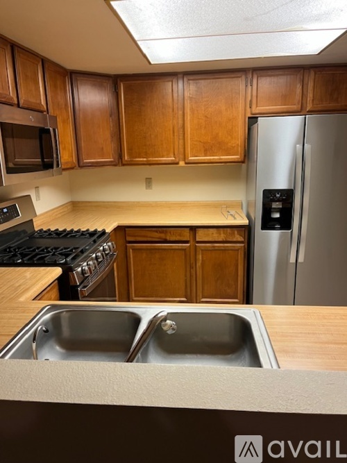 A kitchen with wooden cabinets and a stainless steel refrigerator.