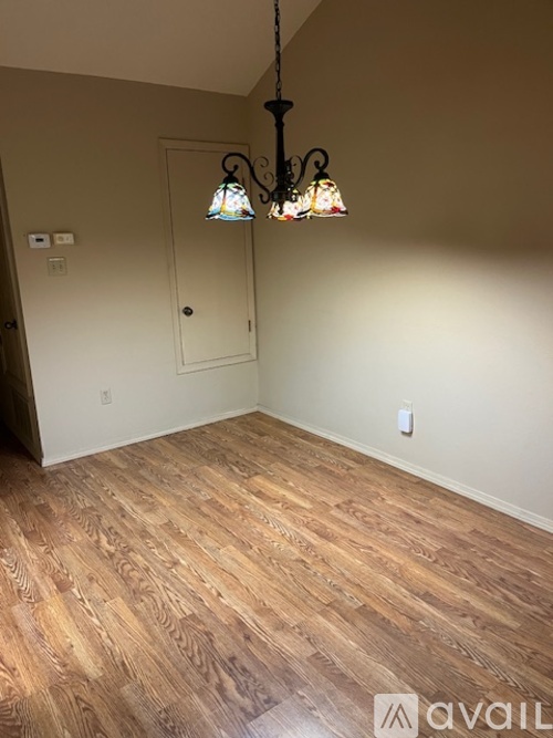 A room with wooden flooring and a chandelier hanging from the ceiling.