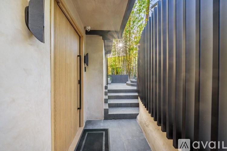 A modern house entrance with a wooden door and a black metal fence.