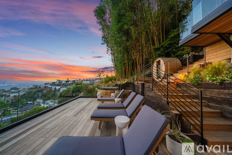 A wooden deck with benches and a railing overlooking a cityscape at sunset.