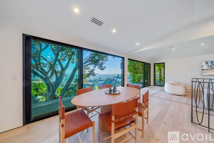 A dining room with a table and chairs and a view of the outdoors through the window.