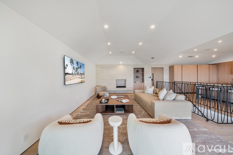 A modern living room with a white sofa set and a painting on the wall.